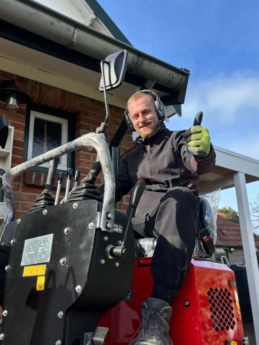 Dennis, eigenaar van Tuinbazen, aan het werk met de minigraver in Zuid-Limburg